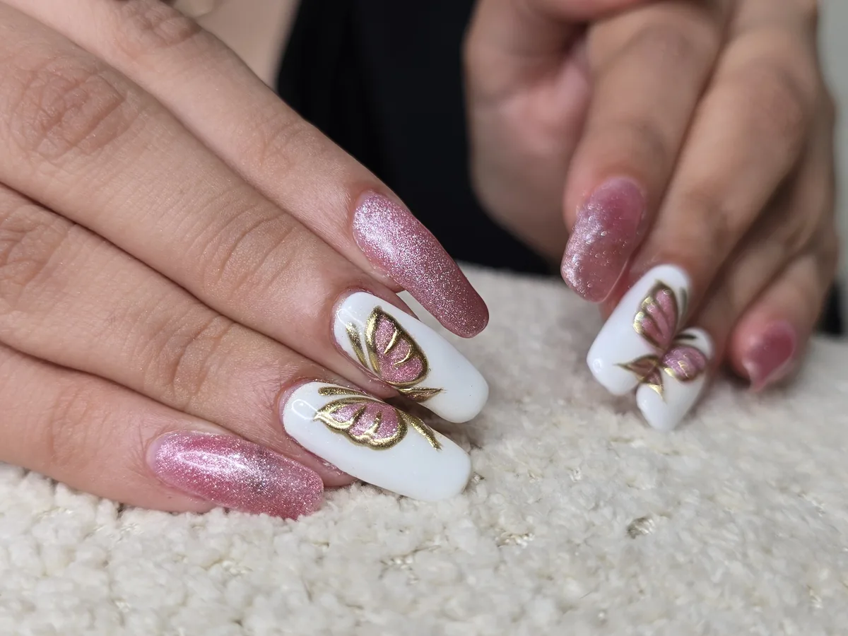 Vue rapprochée d'un papillon souligné d'or sur un ongle en gel blanc, Para Ella Dubaï