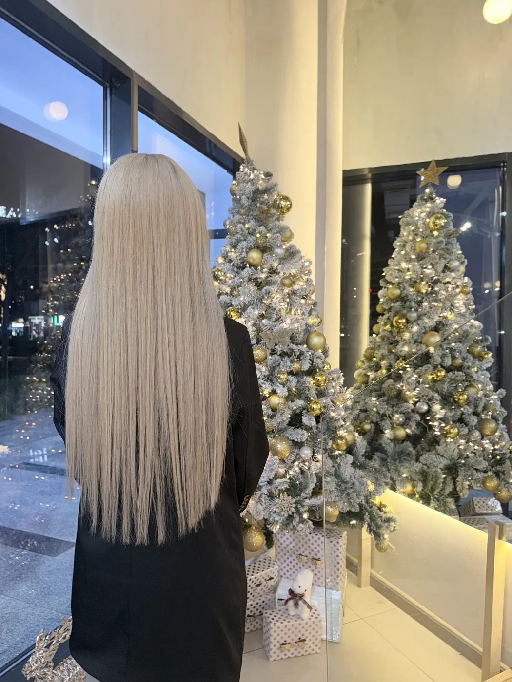Long straight platinum blonde hair seen from behind beside a decorated Christmas tree
