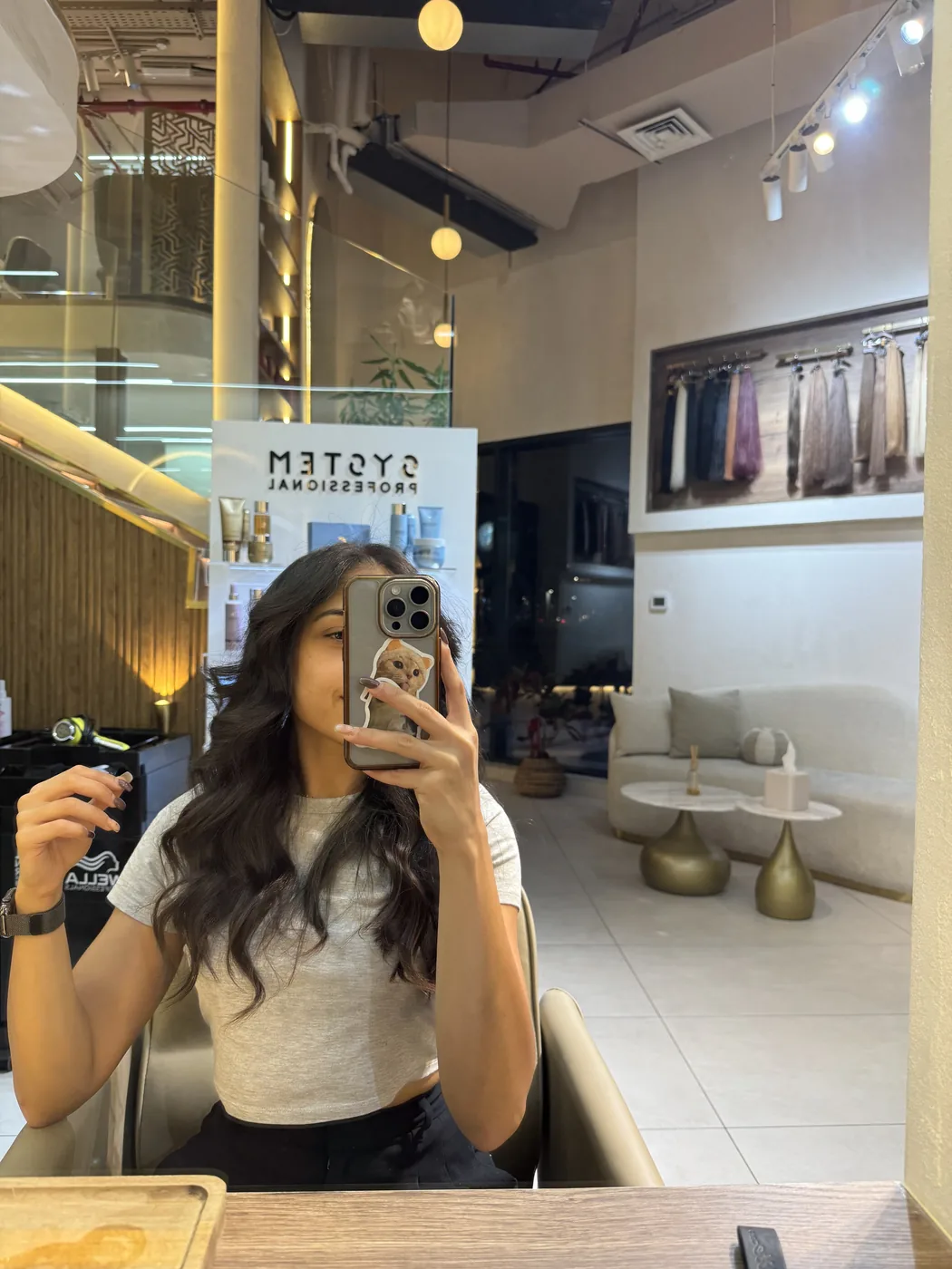 Woman takes a mirror selfie seated in a salon styling chair