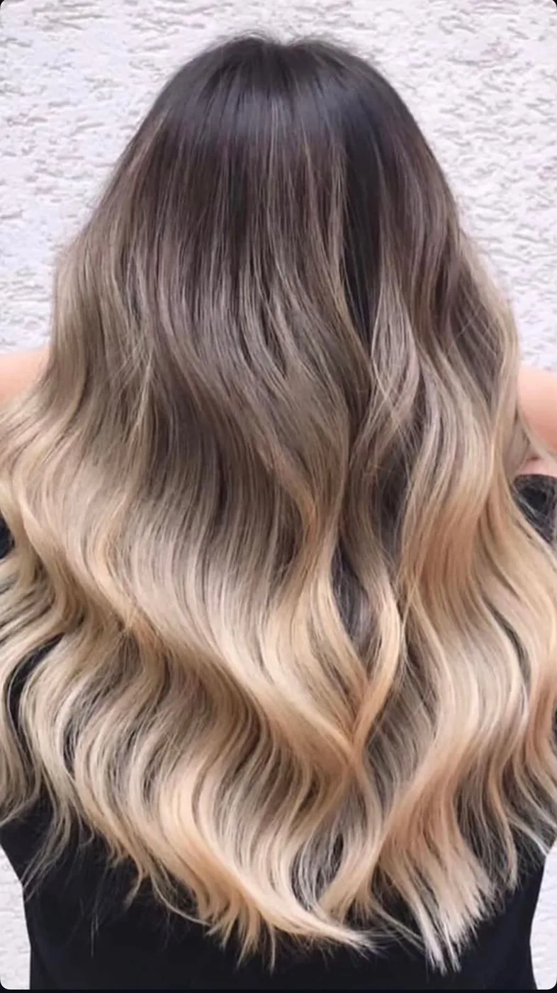 Back view of long wavy hair, dark roots blending into blonde ends