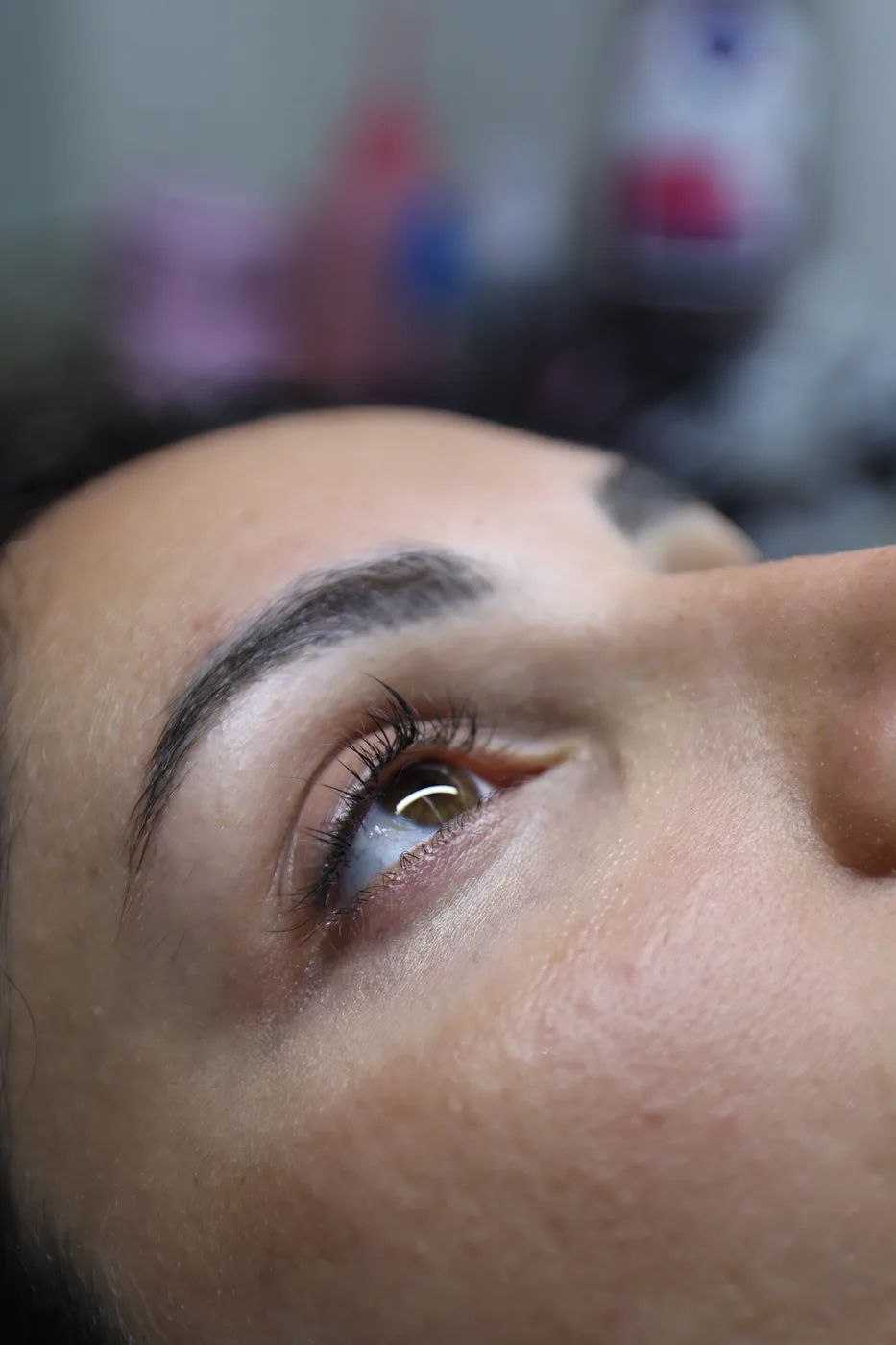 Close-up of a reclining woman's shaped eyebrow, lashes and open eye