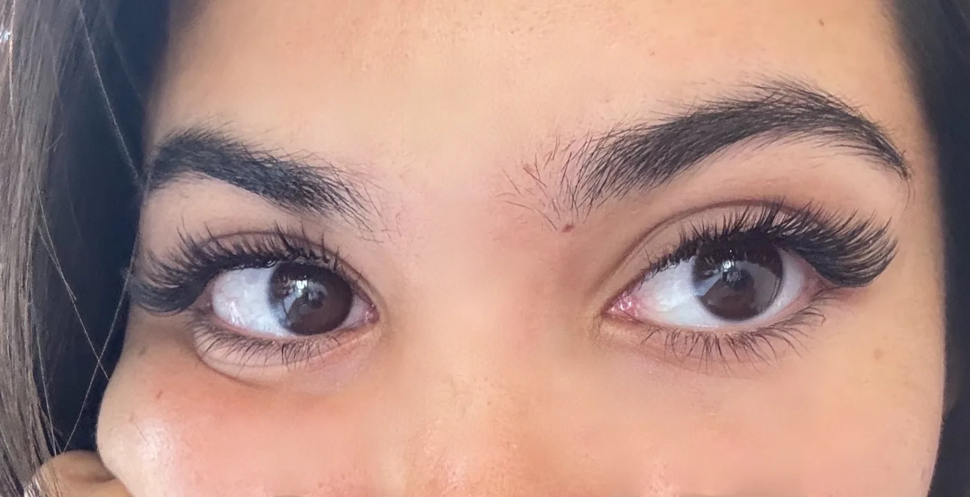 Close-up of a woman's eyes showing long dense dark lashes and thick groomed brows