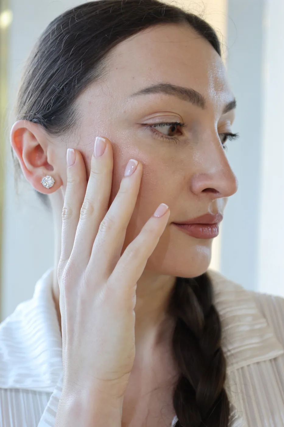Close-up of a woman resting a hand with nude manicure against her cheek
