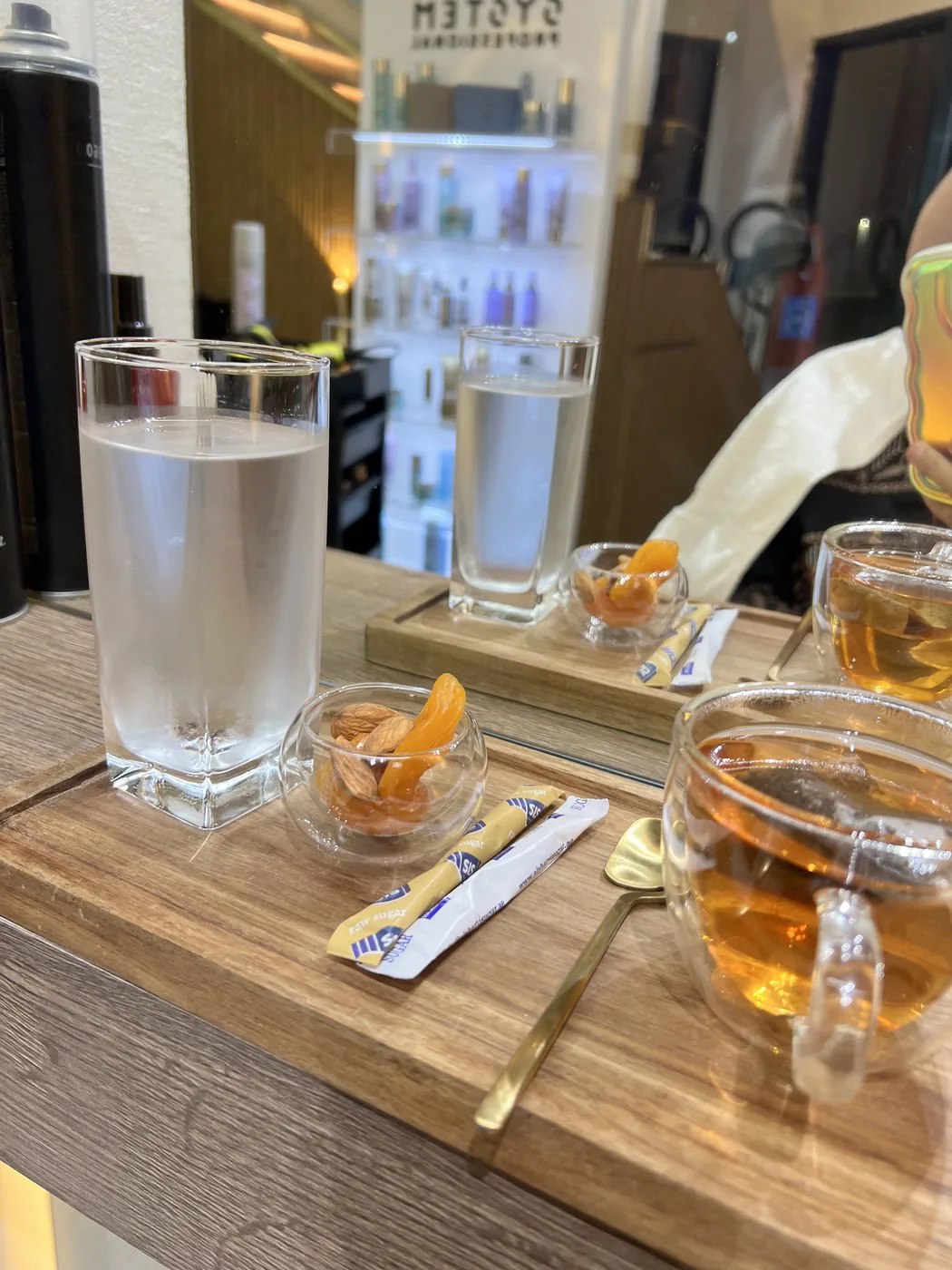 Glass of water, tea cups, dried fruit and nuts on a salon counter