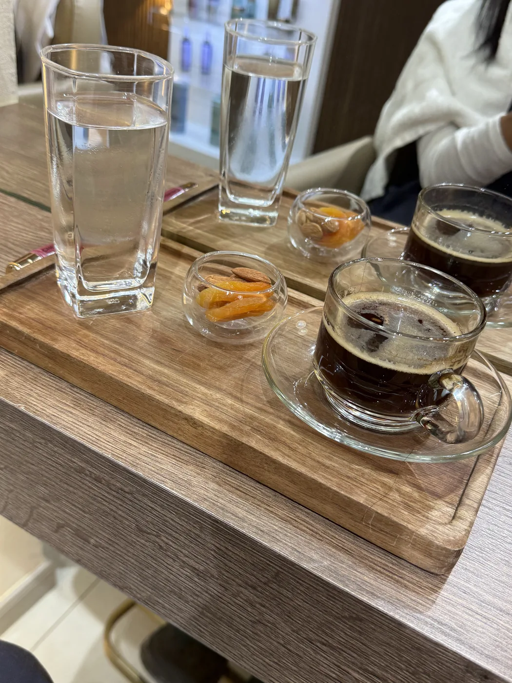 Two glasses of water, black tea and dried fruit on a wooden armrest tray