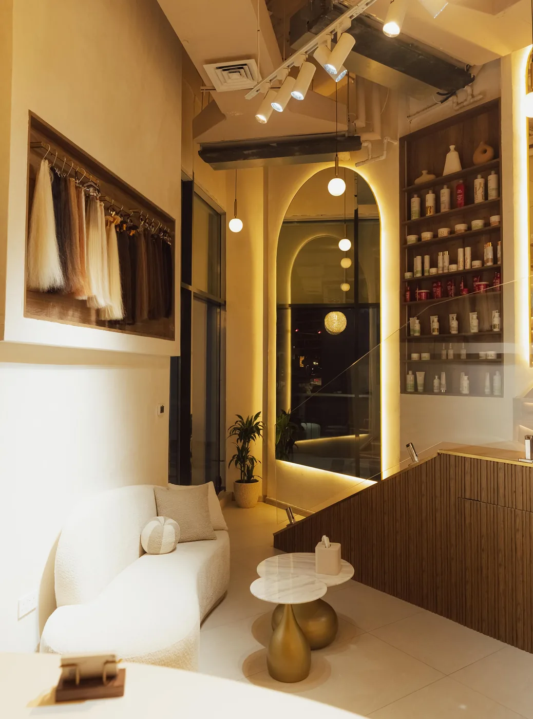 Salon waiting area with cream sofa, marble tables and framed hair-extension photograph