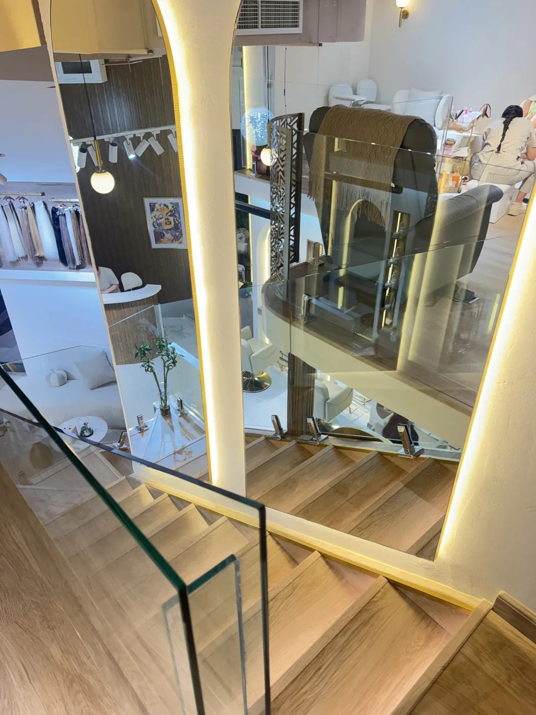 View down a wooden staircase with glass balustrade and lit handrail
