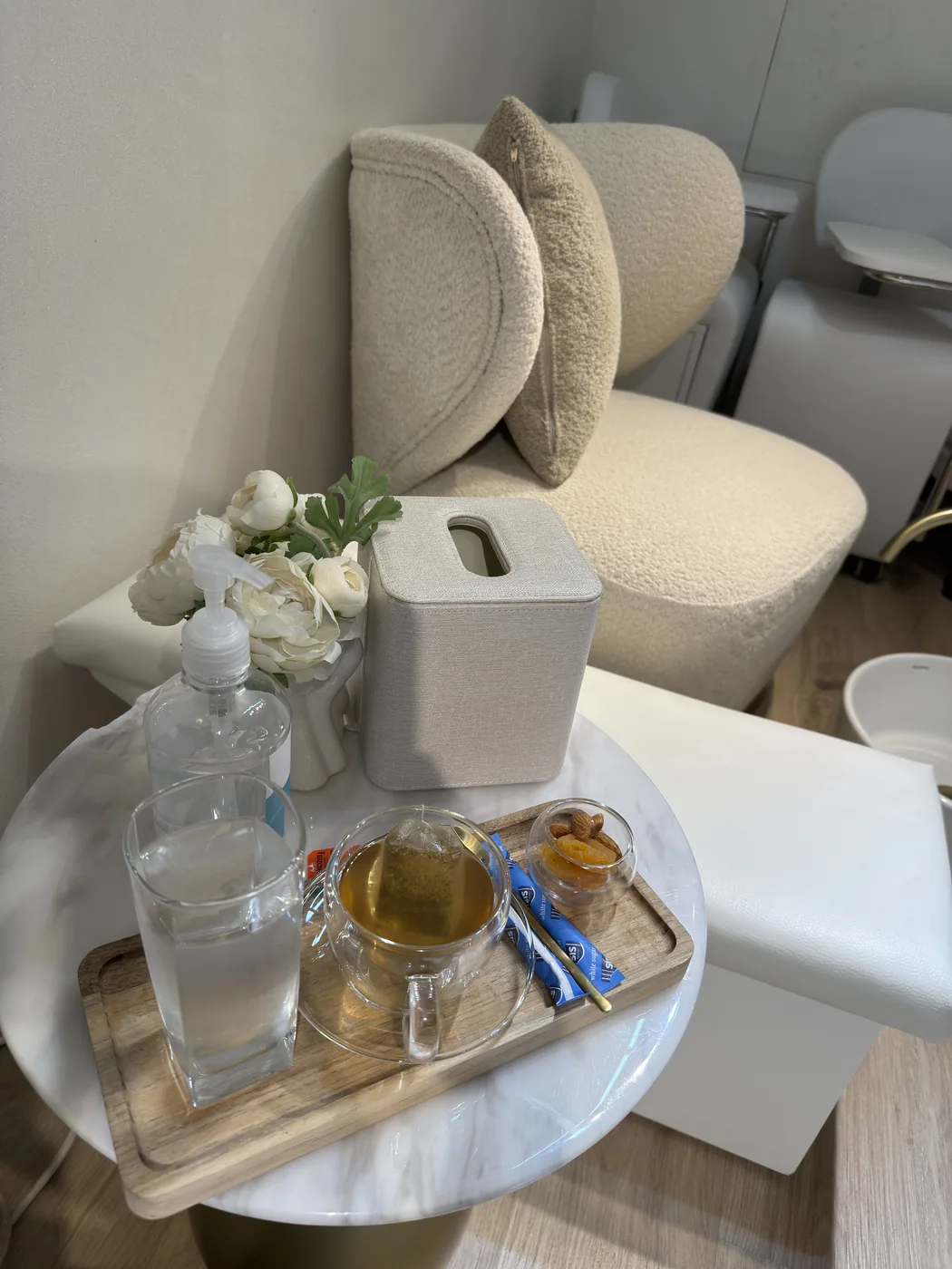Marble side table with water, tea and nuts on a wooden tray